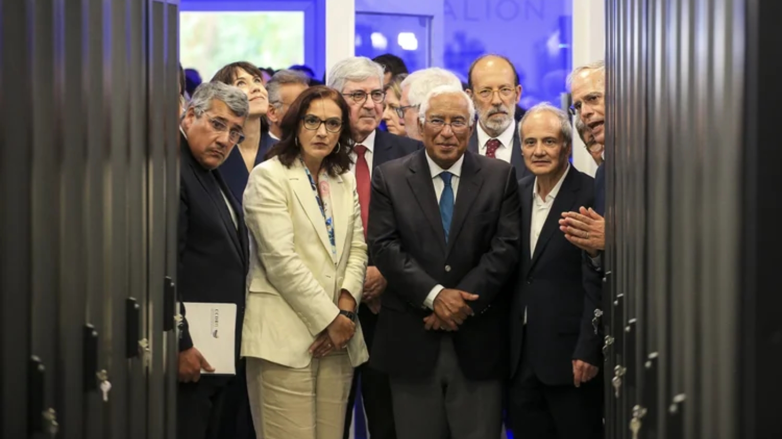 Group of officials and institutional representatives standing between rows of server racks during a visit to a high-performance computing facility, observing the supercomputing infrastructure.