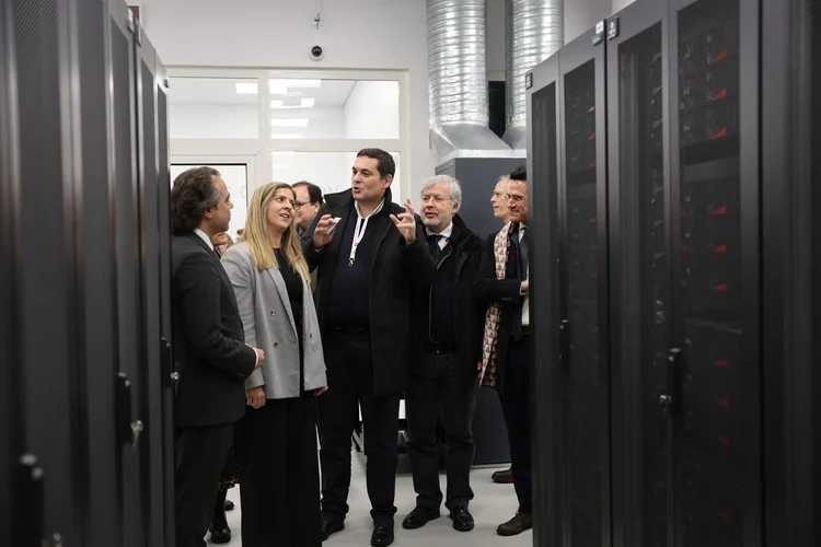 Group of people touring a data centre, standing between server racks while one person explains the infrastructure and equipment.