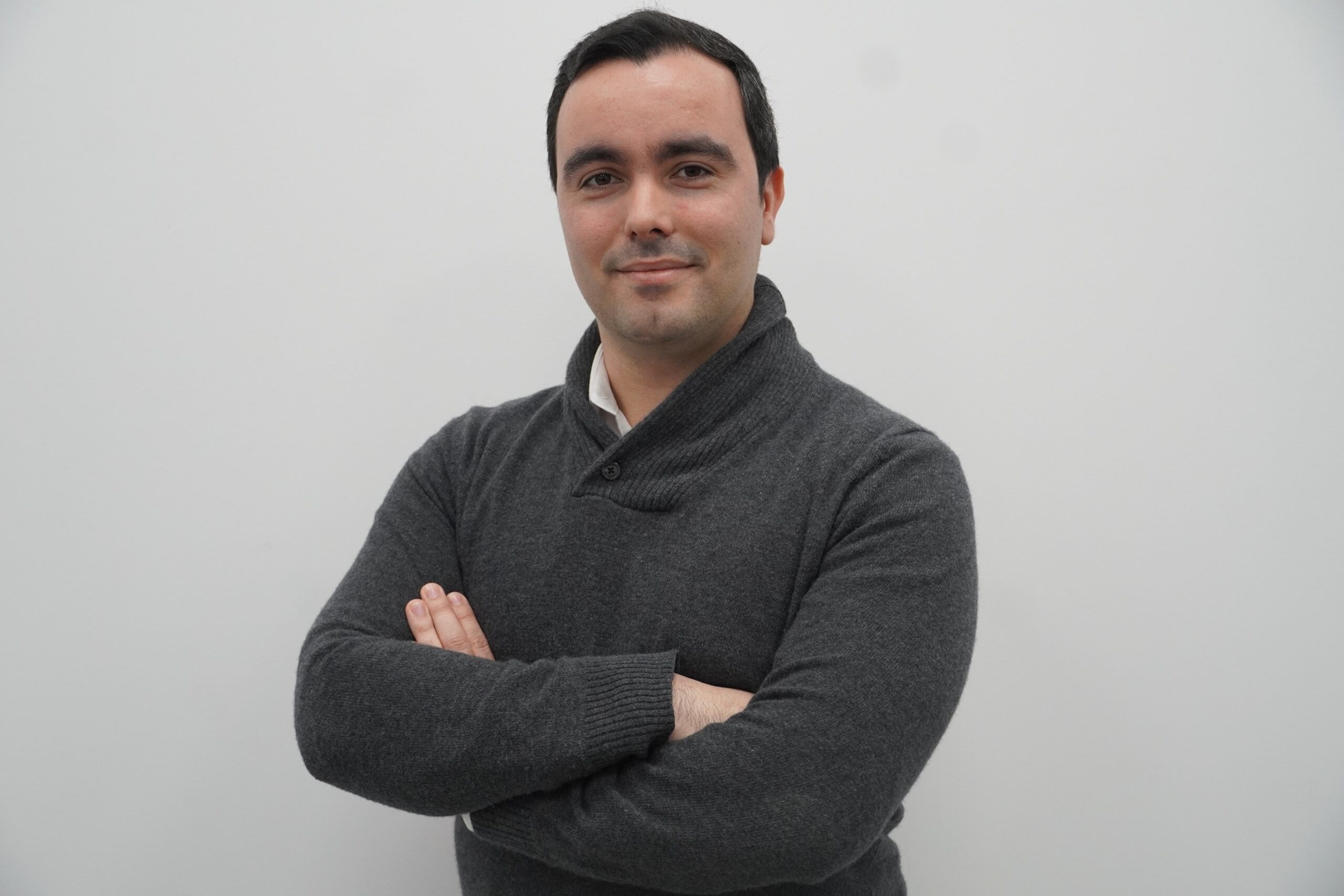 Man wearing a grey sweater with arms-crossed.