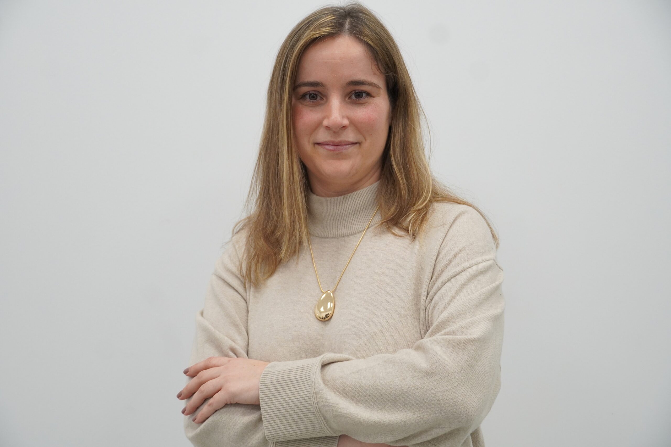 Woman wearing a white sweater with arms-crossed.