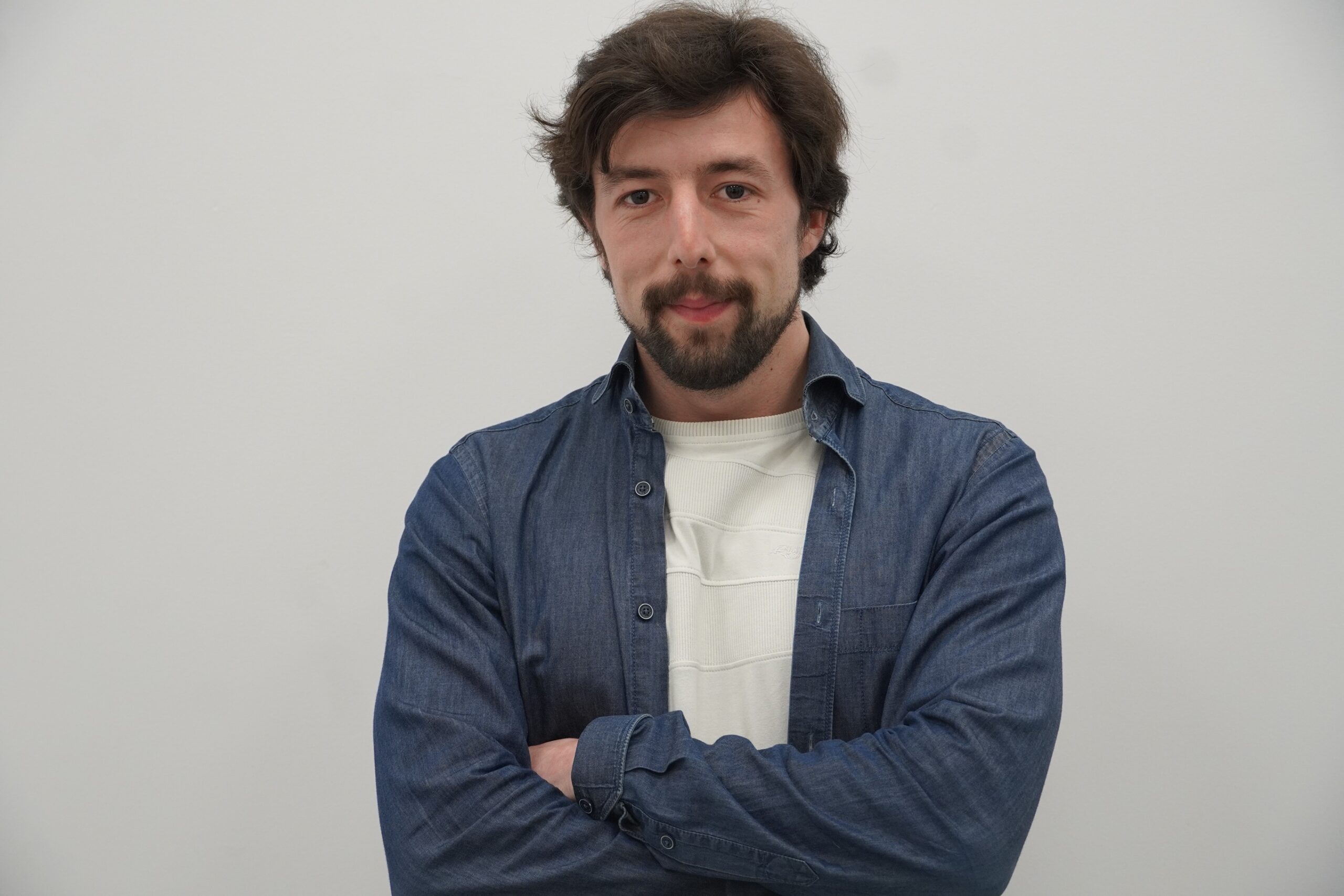 Man wearing a white shirt and blue jacket with arms-crossed.