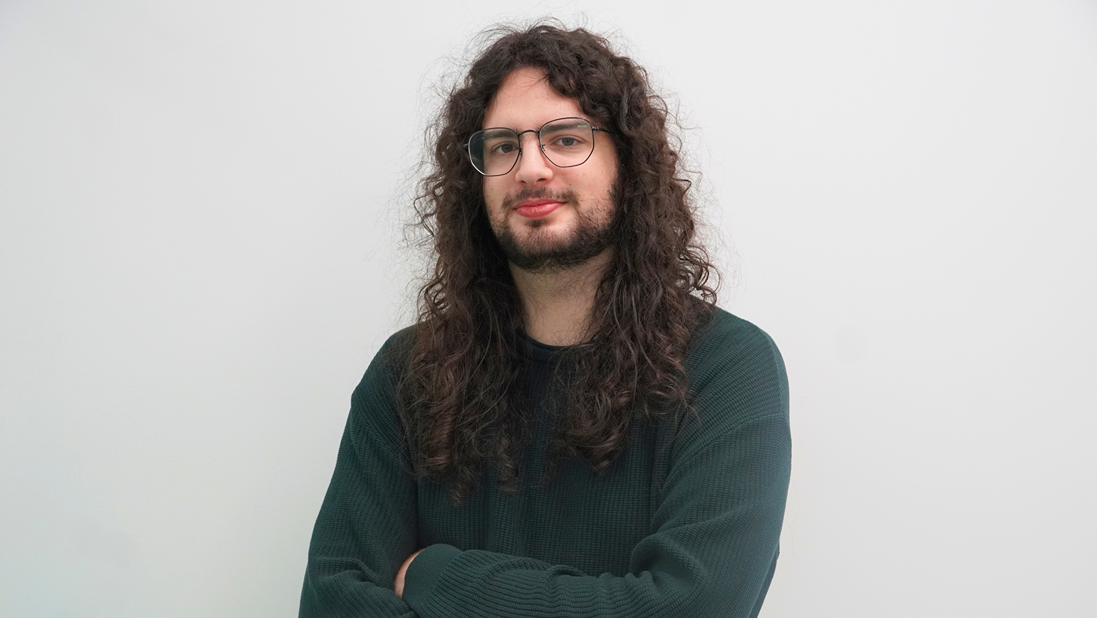 Man with a green sweater posing for a photo.