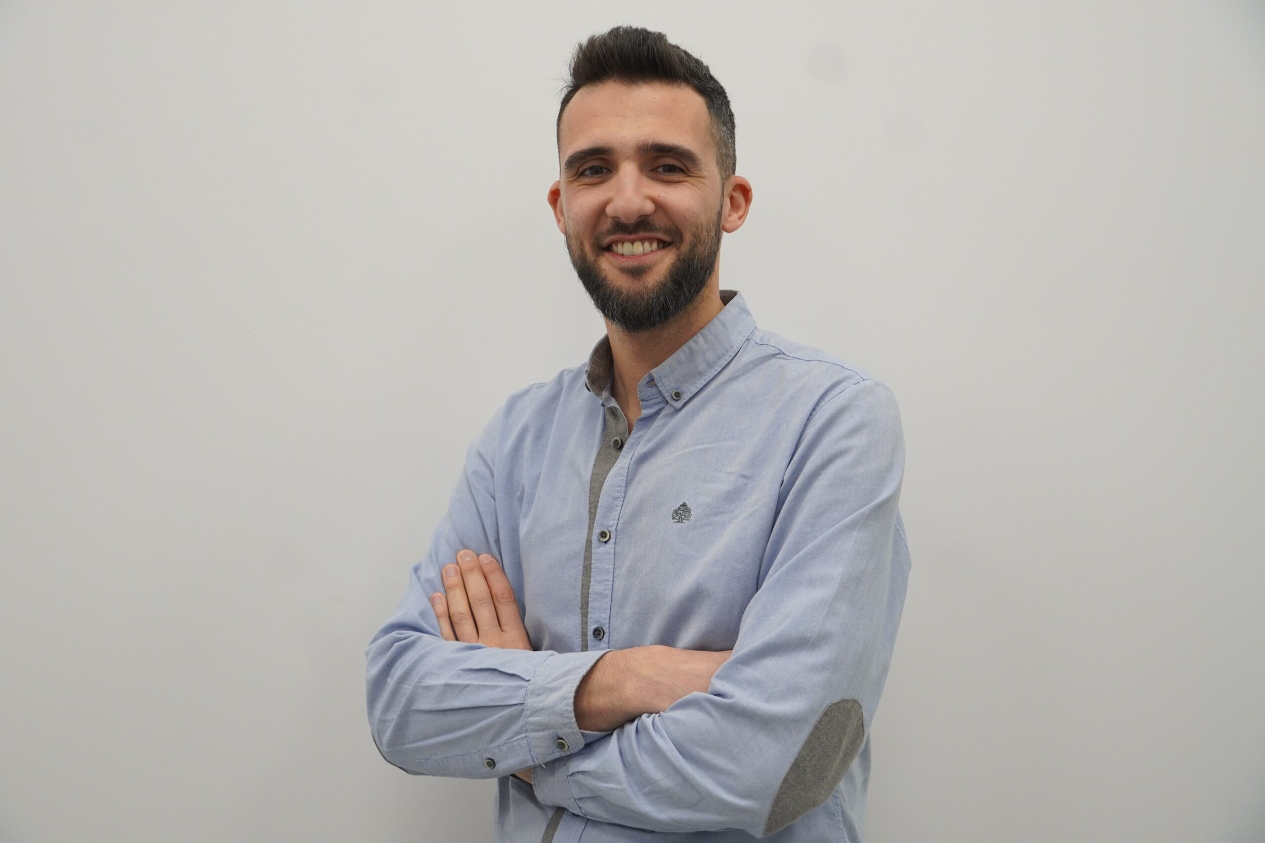 Man wearing a light blue shirt with arms-crossed.