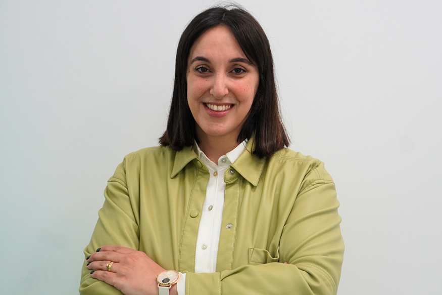 Woman with a green jacket and white blouse posing for a photo.