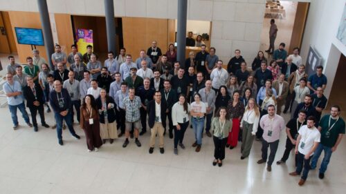 Large group of conference participants gathered in a lobby space, posing together for a group photo during a professional event.