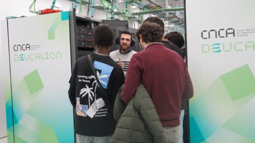 A male researcher with three students in the server corridor.