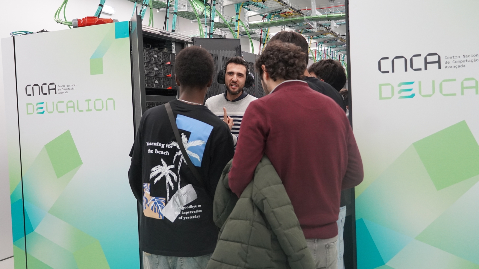 A male researcher with three students in the server corridor.