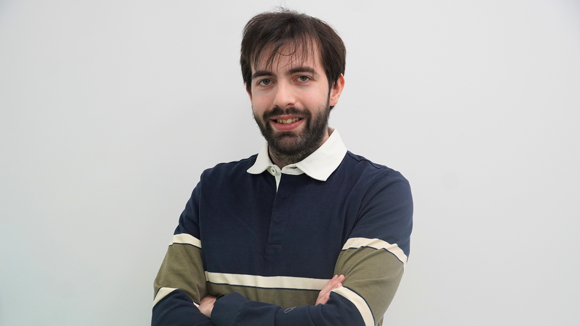 Man with blue and green sweater posing for a photo.