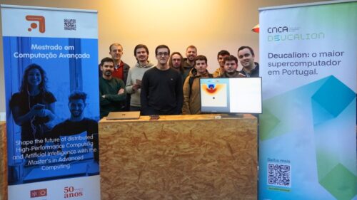Grupo de participantes em pé atrás de um balcão de informações, ladeado por faixas que promovem um mestrado em Computação Avançada e o supercomputador Deucalion, com um monitor a exibir dados visuais no centro.