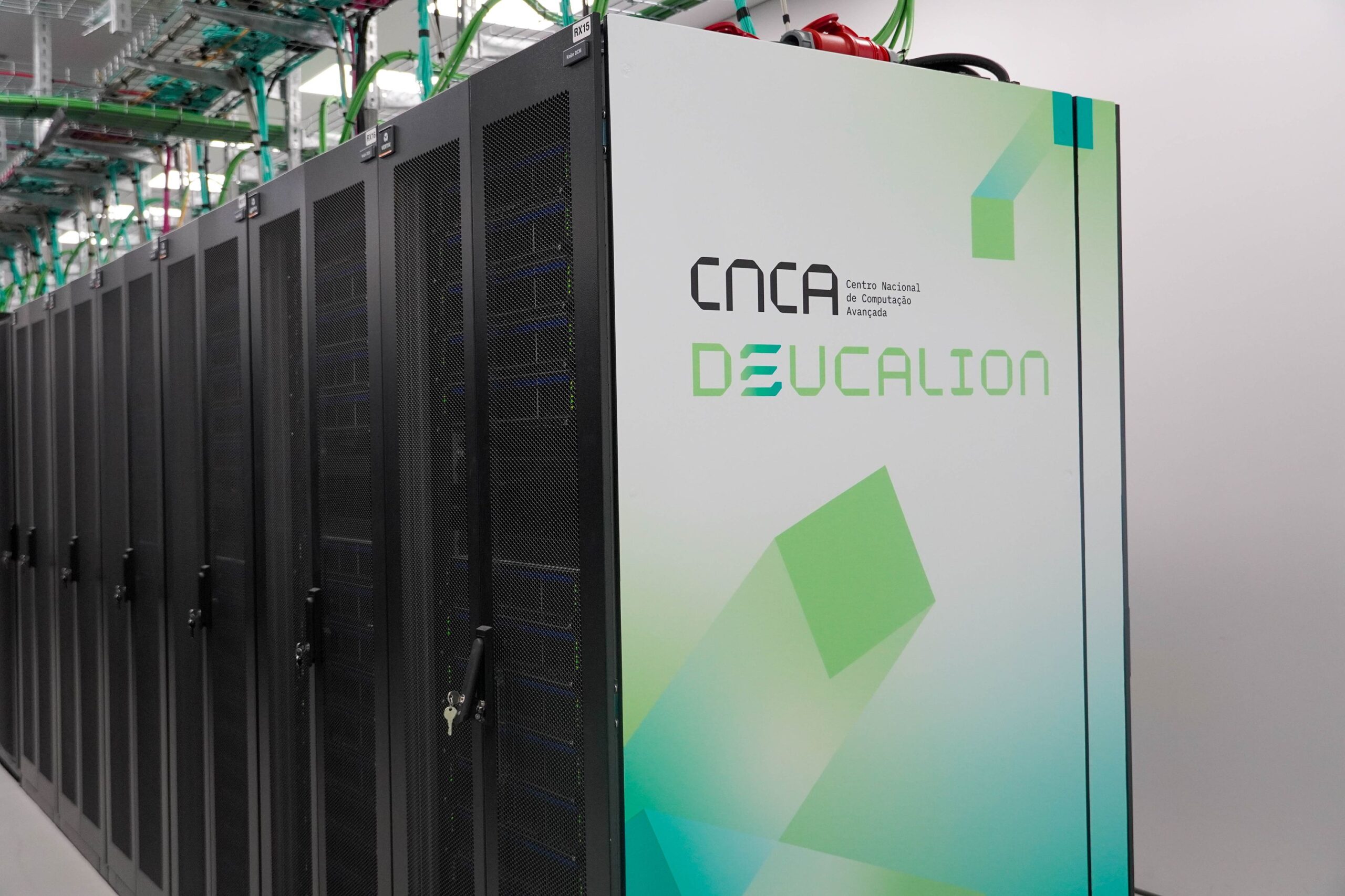 Deucalion supercomputer cabinet inside a data centre aisle, with the DEUCALION logo on the front panel and rows of black server racks extending alongside it.
