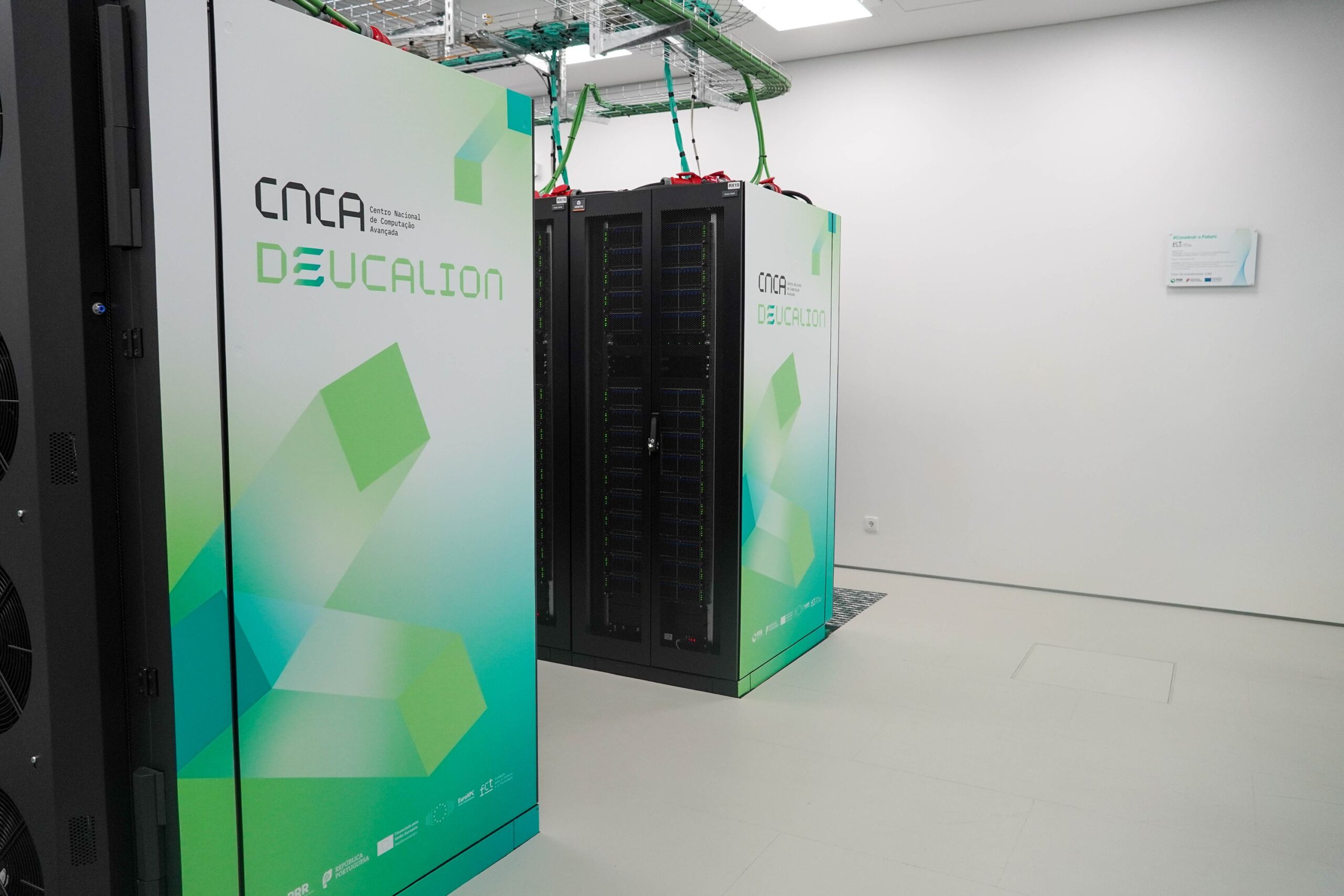 Deucalion supercomputer racks inside a data centre, showing rows of black server cabinets and cooling units with the Deucalion branding on the front panels.