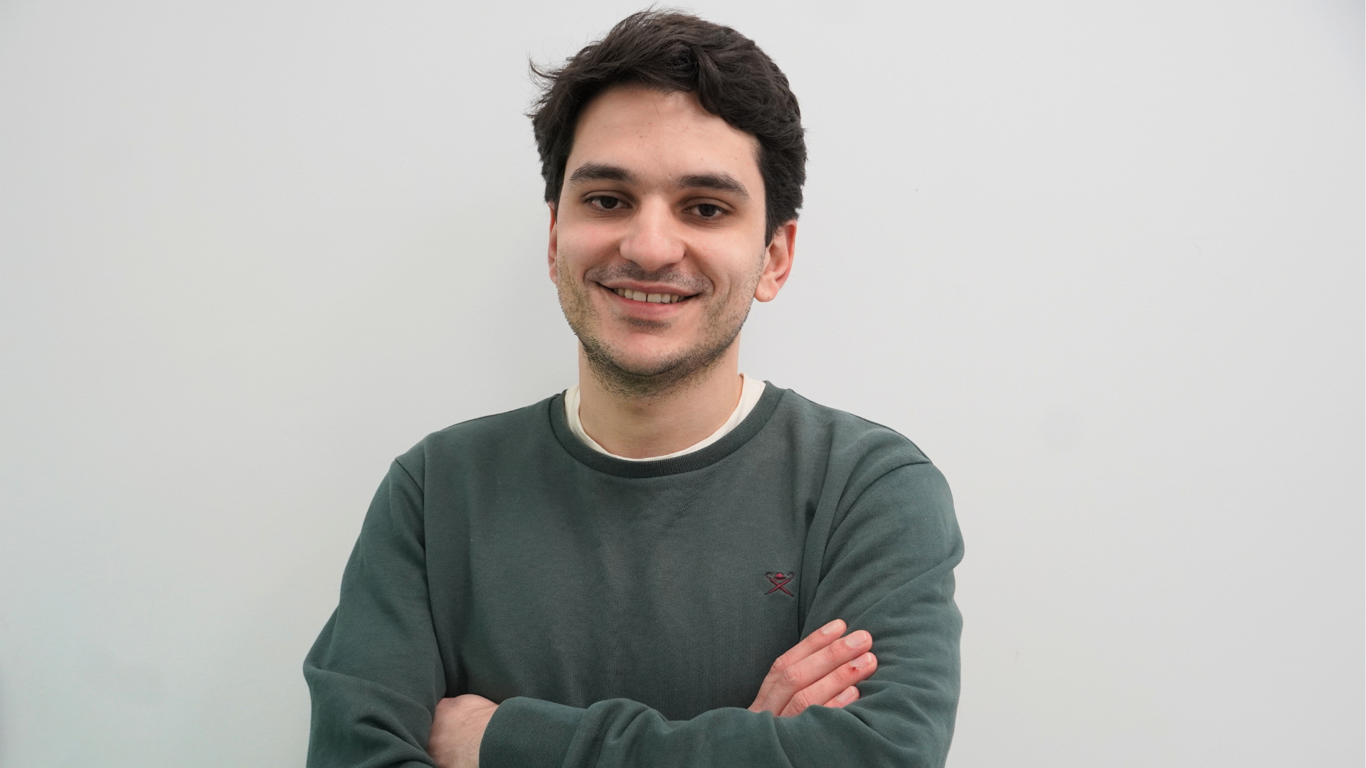 Men wearing a dark green shirt with arms-crossed.