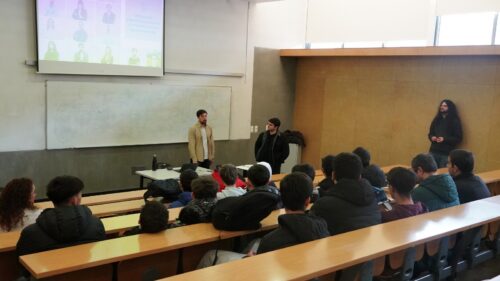 Três investigadores apresentam numa sala de universidade para um grupo de estudantes do ensino secundário, com um slide projetado no ecrã ao fundo.