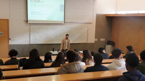 Investigador apresenta o sistema de supercomputação Deucalion a estudantes numa sala de aula universitária, com slides projetados numa tela atrás.