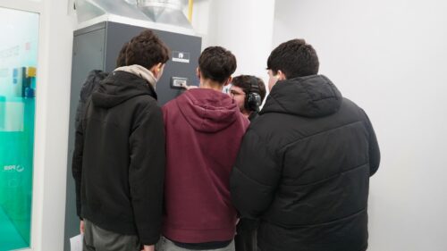 Um grupo de estudantes observa atentamente um supercomputador enquanto um investigador explica como ele funciona.