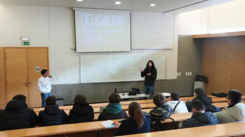 Investigador apresenta o supercomputador Deucalion a um grupo de estudantes numa sala de aula universitária, com slides projetados no ecrã.