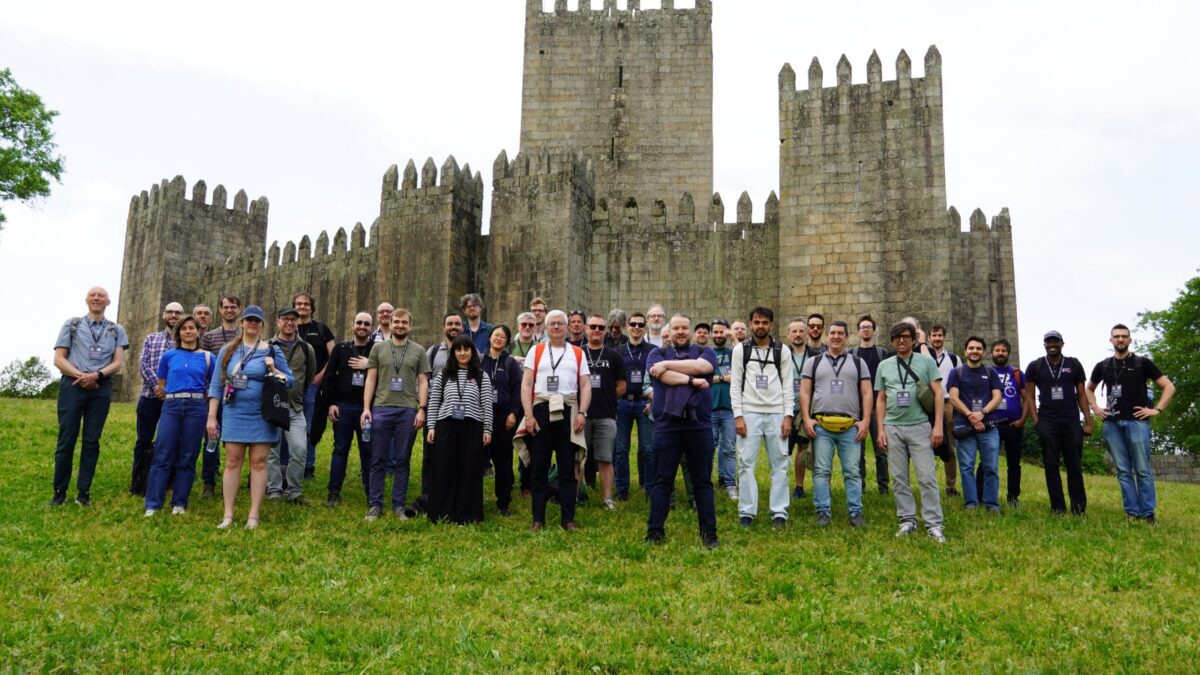 Large group of event participants standing on grass in front of a historic stone castle, likely during a social activity at the EasyBuild User Meeting.