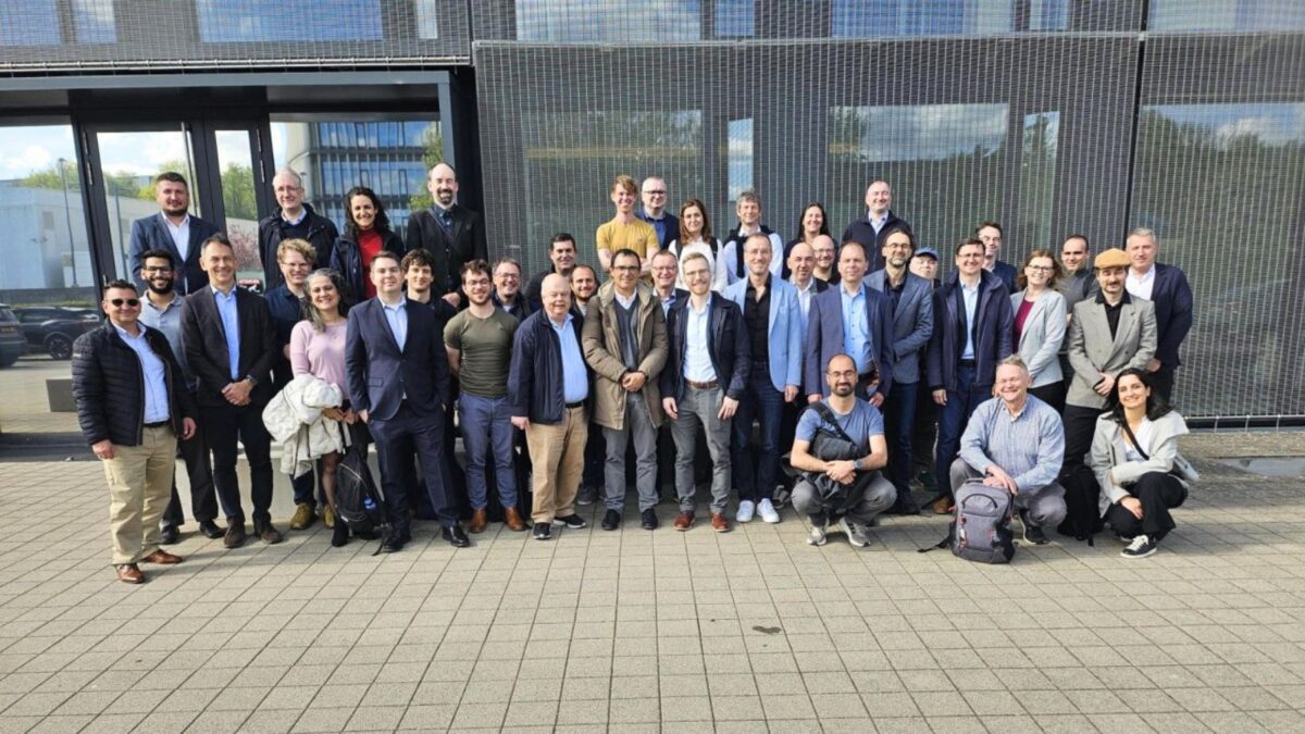 Um grande grupo de profissionais a posar ao ar livre em frente a um edifício moderno durante uma reunião europeia sobre HPC.