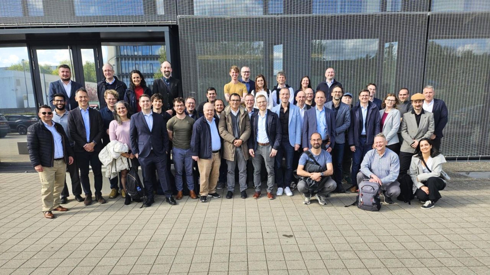 Um grande grupo de profissionais a posar ao ar livre em frente a um edifício moderno durante uma reunião europeia sobre HPC.