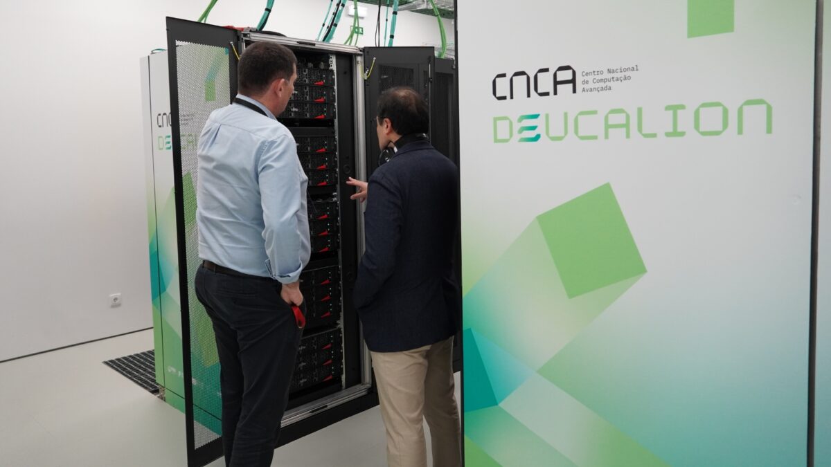 Dois homens examinam o hardware interno de uma cabine do supercomputador Deucalion durante uma visita técnica a uma instalação do Centro Nacional de Computação Avançada (CNCA).