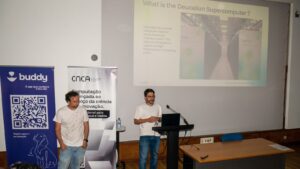 Two speakers present how the Deucalion supercomputer supports advanced computing and AI, with presentation slides displayed during a CNCA event.