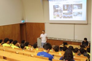 Um orador discute as aplicações da computação de alto desempenho com um grupo de estudantes numa sala de aula da universidade.